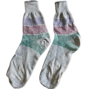 May include: A pair of ankle-length socks featuring a heather gray base color. The upper section of each sock displays horizontal stripes in shades of lavender, mauve, and teal, while the foot and toe areas remain a solid heather gray color.