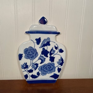 May include: A white ceramic vase with a blue and white floral design. The vase is shaped like a traditional Chinese ginger jar.