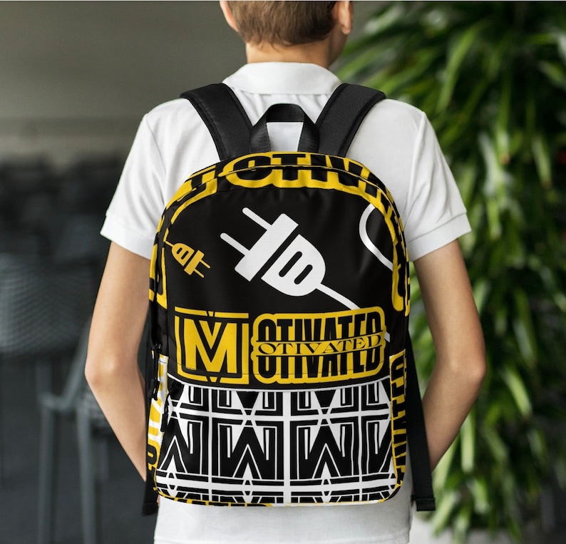 K&ouml;nnte beinhalten: Schwarzer Rucksack mit gelbem und wei&szlig;em Design. Der Rucksack hat eine gro&szlig;e wei&szlig;e Steckergrafik und die W&ouml;rter "Motivated" und "Otivated" in gelben Buchstaben.
