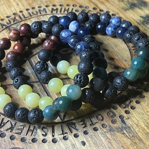 May include: Four beaded bracelets with black lava rock beads, green agate beads, yellow jade beads, and blue sodalite beads.