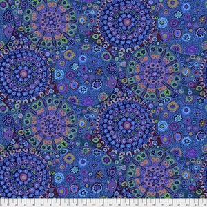 以下が含まれることがあります： カラフルな円と花が繰り返し描かれた青い布。円は、小さな点と花が同心円状に並んだマンダラのようなデザインです。
