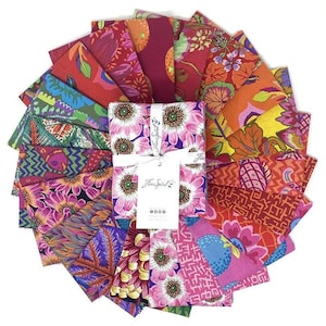 Op de afbeelding: Een cirkelvormige opstelling van rechthoekige stofstalen met diverse bloemmotieven, geometrische en abstracte patronen in levendige tinten roze, oranje, rood, paars en groen. Een wit papieren label met de tekst Free Spirit is in het midden bevestigd.