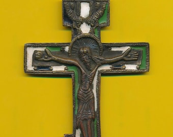 Puede incluir: Una cruz de bronce con detalles de esmalte. La cruz presenta una representación de Jesucristo en la cruz, con un fondo verde, blanco y azul. La cruz tiene un bucle en la parte superior para colgar.