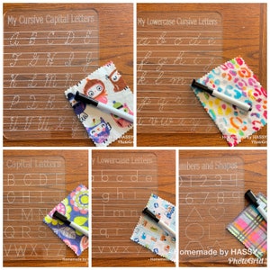 May include: Four clear plastic dry-erase boards with white lines and dotted lines for tracing letters and numbers. The boards are labelled "My Cursive Capital Letters", "My Lowercase Cursive Letters", "Capital Letters", "My Lowercase Letters", and "Numbers and Shapes". Each board has a colourful fabric square next to it and a black and white dry-erase marker.