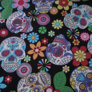Könnte beinhalten: Ein schwarzer Stoff mit einem sich wiederholenden Muster aus bunten Zucker Totenköpfen und Blumen. Die Totenköpfe sind weiß mit schwarzen Umrissen und haben bunte Details wie Herzen, Blumen und Wirbel. Die Blumen sind in verschiedenen Farben, darunter rosa, gelb, rot und blau.