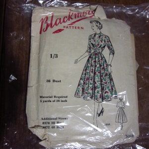 Op de afbeelding: Vintage "Blackmor Pattern" naaipatroon, verzegeld in plastic. Het patroon toont een tekening van een vrouw in een bloemenjurk. De tekst geeft een borstomvang van 91 cm aan en vereist 4,57 meter stof van 91 cm.