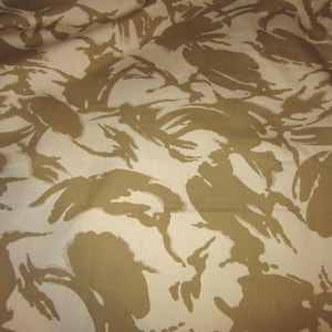 May include: A close-up of a fabric with a camouflage pattern. The pattern is made up of brown and beige shapes that resemble abstract leaves. The fabric has a soft, textured feel.