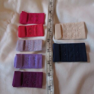Pode incluir: Conjunto de seis extensões de sutiã em várias cores, incluindo rosa, vermelho, roxo e azul. As extensões são feitas de tecido e têm três filas de ganchos e ilhós.