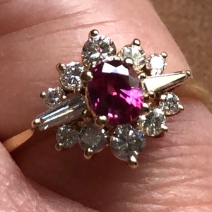 May include: A gold ring with a large pink gemstone surrounded by smaller diamonds.