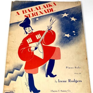 May include: Sheet music cover titled "A Balalaika Serenade" featuring a stylized illustration of a person in a red and white outfit playing a balalaika. The background is blue with white stars. The text "Piano Solo" and the author's name are also visible.
