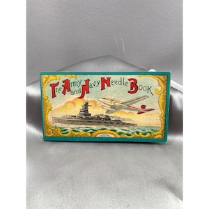 以下が含まれることがあります： ヴィンテージの「The Army and Navy Needle Book」で、ティール色の縁取りが施されています。表紙には戦艦、飛行機、タイトルが赤とネイビーで描かれています。背景は薄い青色で、金色の装飾的な縁取りが施されています。