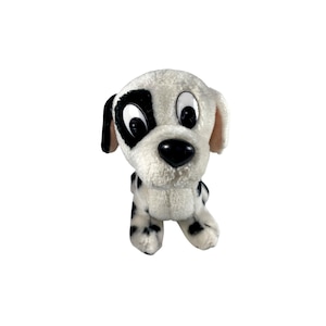 May include: A plush Dalmatian dog toy with a white body and black spots. The dog has large, expressive eyes, a black nose, and black patches around one eye and on its ears. The toy is soft and cuddly, perfect for children.
