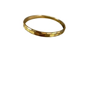 Könnte beinhalten: Ein goldfarbenes Armreif-Armband mit geometrischem Design. Das Armband hat eine Reihe rechteckiger Formen um seinen Umfang. Der Schmuck ist vor einem weißen Hintergrund platziert.