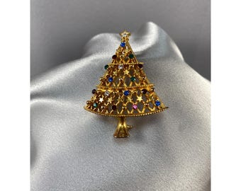 May include: A gold-tone Christmas tree brooch with a filigree design and colorful rhinestones.