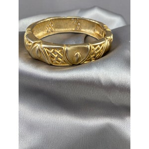 Gold tone metal hinged bracelet.  Soft looking gold with pressed design. Vintage 70s