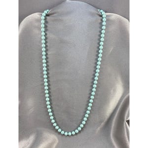 Pode incluir: Um longo fio de contas de pérola azul claro.