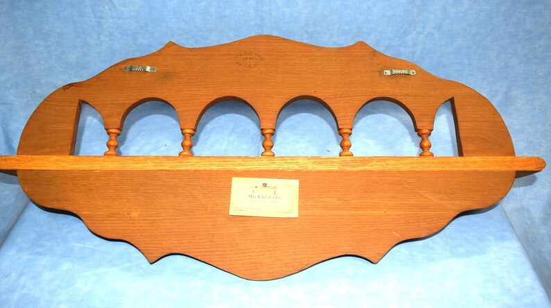 May include: A wooden wall shelf with a scalloped edge and five arches. The shelf has a label that reads "J.T. Beaulieu Co."