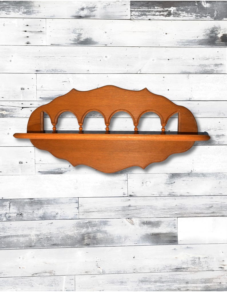 May include: A wooden shelf with a decorative, scalloped edge and five arched openings. The shelf is stained a rich brown color.