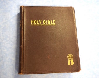 May include: A brown leather-bound Holy Bible with gold lettering on the cover. The book has a gold ribbon with the text "Blue Ribbon Edition" on it.