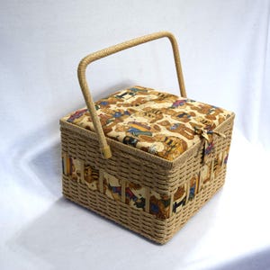 May include: A rectangular sewing basket with a woven wicker exterior and a fabric-covered lid. The lid and sides feature a repeating pattern of teddy bears in various outfits. The basket has a woven handle and a fabric tie closure.