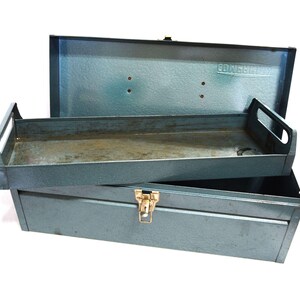 May include: Open, vintage metal toolbox in a teal-gray color. The toolbox has a tray and a hinged lid. The lid is open, revealing the interior. The toolbox is made of metal and has a gold-colored clasp.