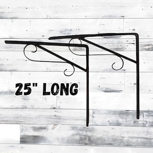 May include: Two black metal decorative brackets, each 25 inches long, with a scrolled design. The brackets are designed to be mounted on a wall and provide support for shelves or other items. The text "25" LONG" is displayed on the image.