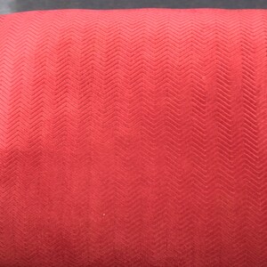 May include: Red fabric with a chevron pattern. The fabric has a soft, textured surface.