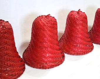 May include: Four red woven bell-shaped objects are arranged in a row against a white background. The objects have a flared base and a rounded top with a small loop. The woven texture is visible.