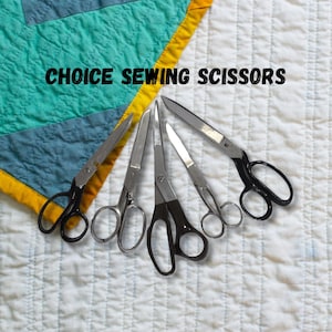 May include: A collection of sewing scissors with black and silver handles, arranged on a white quilted surface. The text "CHOICE SEWING SCISSORS" is displayed above the scissors. The scissors vary in size and design.