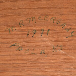 May include: Close-up of a wooden surface with handwritten text that reads "R.M.C.R.A.Y. 1911 POLA, WIS."