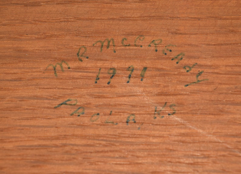 May include: Close-up of a wooden surface with handwritten text that reads "R.M.C.R.A.Y. 1911 POLA, WIS."