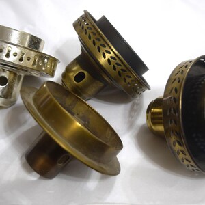May include: Four different metal lamp finials with decorative edges. The finials are in various shades of gold and black.
