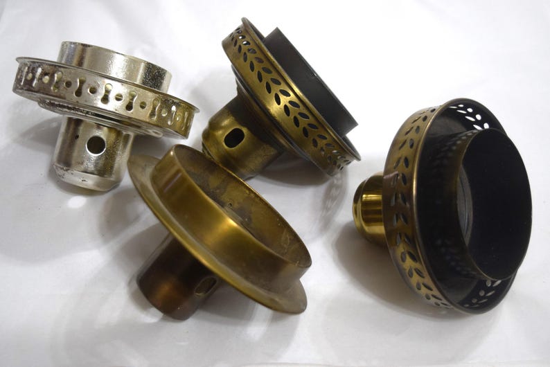 May include: Four different metal lamp finials with decorative edges. The finials are in various shades of gold and black.