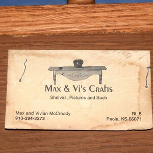 May include: A business card for Max & Vi's Crafts, which specializes in shelves, pictures, and other crafts. The card features a small illustration of a table and the text "Max & Vi's Crafts, Shelves, Pictures and Such, Max and Vivian McCready, 913-294-3272, Rt. 5, Pacla, KS 66071."
