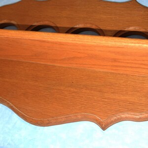 May include: A wooden wall shelf with a scalloped edge and five round cutouts. The shelf is stained a rich brown color.
