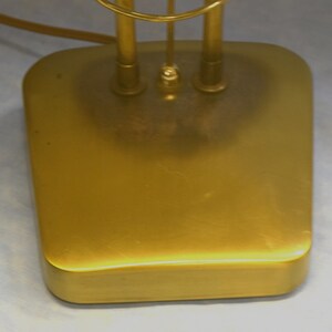 K&ouml;nnte beinhalten: Ein goldfarbener Lampenfu&szlig; aus Metall mit abgerundeter rechteckiger Form.