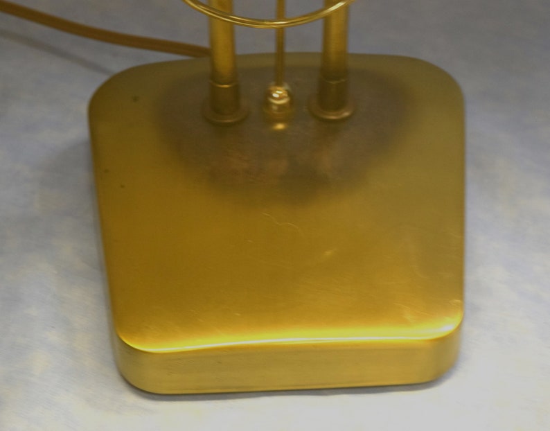 K&ouml;nnte beinhalten: Ein goldfarbener Lampenfu&szlig; aus Metall mit abgerundeter rechteckiger Form.