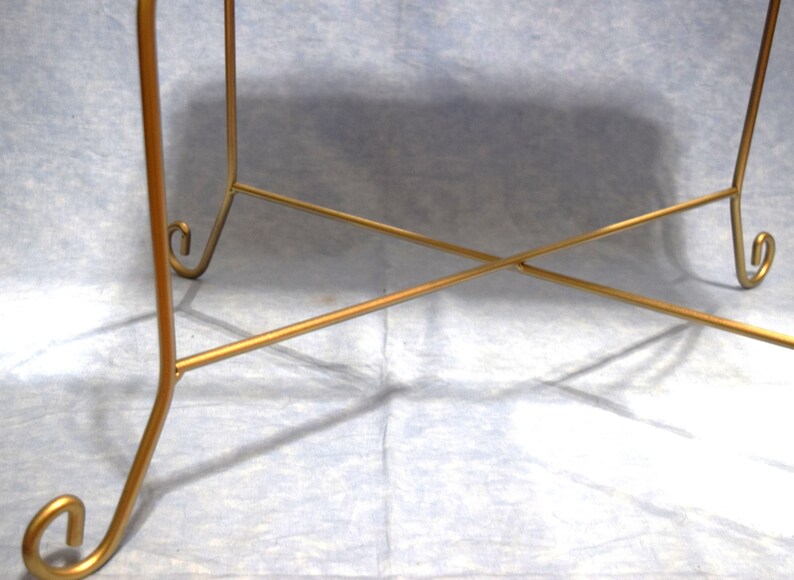 May include: Gold metal table base with a criss-cross design and curled feet.
