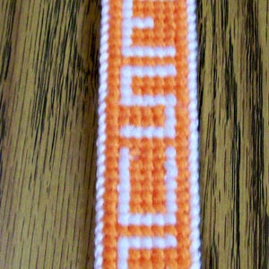 May include: Orange and white plastic canvas bookmark with the word "Jesus" stitched in white.