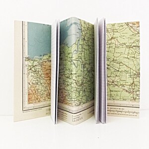 May include: Three vintage-style notebooks with maps printed on the covers. The maps are in shades of green, brown, and blue, and show a variety of roads, rivers, and towns. The notebooks are bound in white and have lined pages.