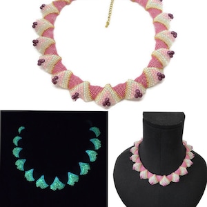 May include: A pink and white beaded necklace with a gold clasp. The necklace is made of small, iridescent beads that are arranged in a spiral pattern. The necklace glows in the dark, with the beads emitting a green light.