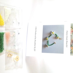 May include: A kit for making a daisy chain bracelet. The kit includes white, yellow, pink, and green beads, a spool of white thread, and a gold clasp. The kit also includes instructions for making the bracelet.