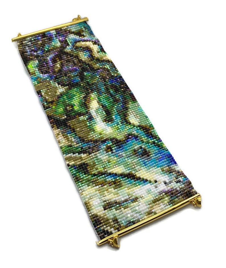 K&ouml;nnte beinhalten: Ein Armband aus Perlen mit einem farbenfrohen, abstrakten Muster. Das Armband besteht aus kleinen, schillernden Perlen und hat einen goldenen Metallverschluss.