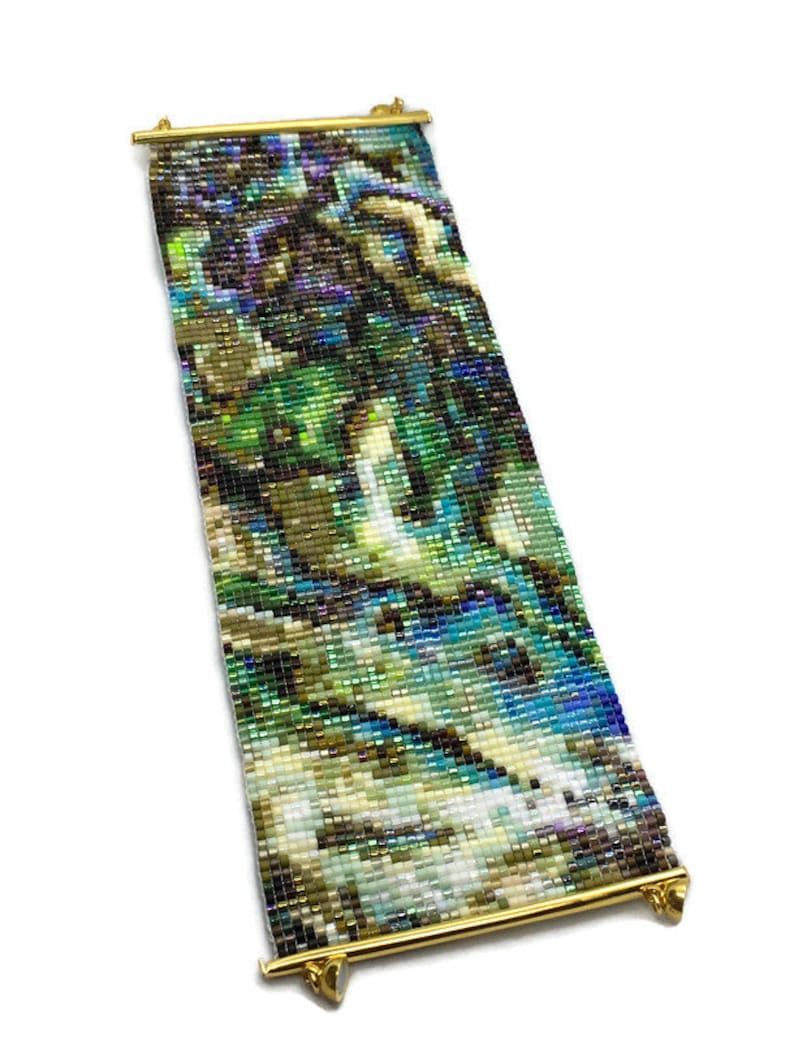 K&ouml;nnte beinhalten: Ein Armband mit bunten Perlen und einem abstrakten Design. Das Armband besteht aus kleinen, bunten Perlen, die zu einem einzigartigen und komplizierten Muster gewebt sind. Das Armband ist an einer goldenen Metallstange mit zwei goldenen Metallverschl&uuml;ssen befestigt.