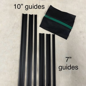 May include: Black guides, labeled as 10" and 7", are arranged on a light-colored surface. A small black leather pouch with a green zipper is also present. The guides appear to be made of a textured material.