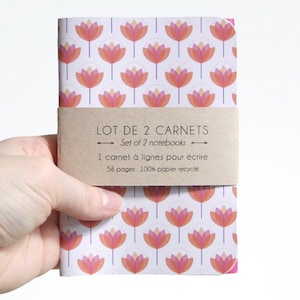 Puede incluir: Conjunto de dos cuadernos con un diseño floral con flores rosas y naranjas sobre un fondo blanco. Los cuadernos están envueltos en papel marrón con el texto "LOT DE 2 CARNETS" y "Set of 2 notebooks" en inglés y francés. El texto también incluye "1 carnet à lignes pour écrire" y "56 pages. 100% papier recycle".
