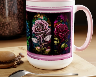 Può includere: Una tazza in ceramica bianca con un bordo e un manico rosa. La tazza presenta un design a vetri colorati con tre rose colorate in una cornice nera. Il design è circondato da un bordo di glitter rosa.