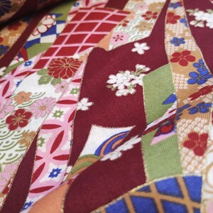 May include: Red, green and gold fabric with a Japanese-inspired pattern of flowers, geometric shapes and stylised waves.