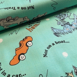 May include: A light turquoise fabric featuring a repeating pattern of Dr. Seuss illustrations, including orange cars, blue boats, and text that reads "Not on a train," "Not on a boat," "Not in a car," and "I do not like green eggs and ham."