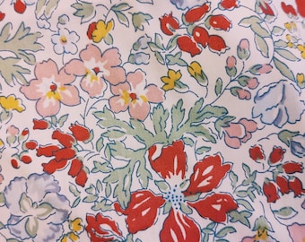 Pode incluir: Um tecido branco com um padrão floral com flores rosa, vermelhas e amarelas com folhas verdes.